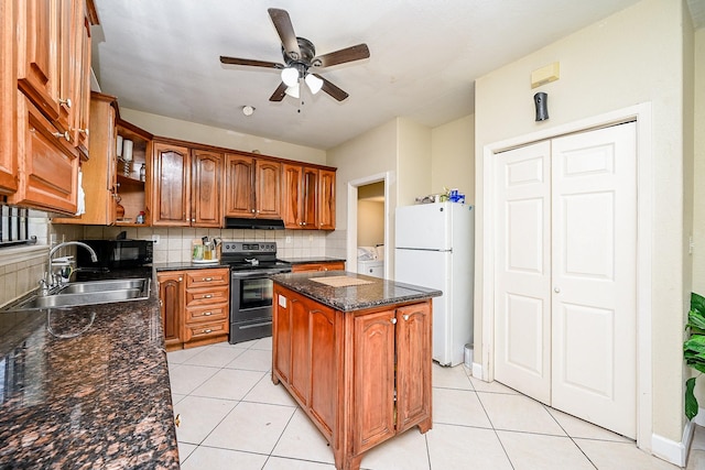 kitchen featuring backsplash, sink, white refrigerator, a kitchen island, and stainless steel electric range