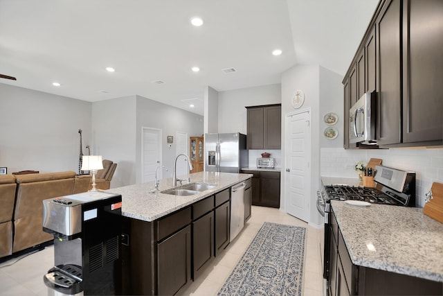 kitchen featuring appliances with stainless steel finishes, backsplash, light stone counters, sink, and light tile patterned flooring