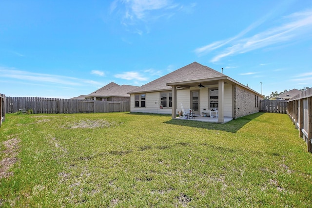 back of house featuring a lawn, ceiling fan, and a patio area