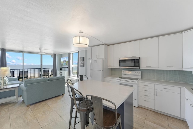 kitchen with white cabinetry, white refrigerator, backsplash, electric stove, and a water view