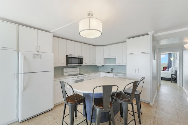 kitchen featuring tasteful backsplash, a breakfast bar, white appliances, sink, and white cabinetry