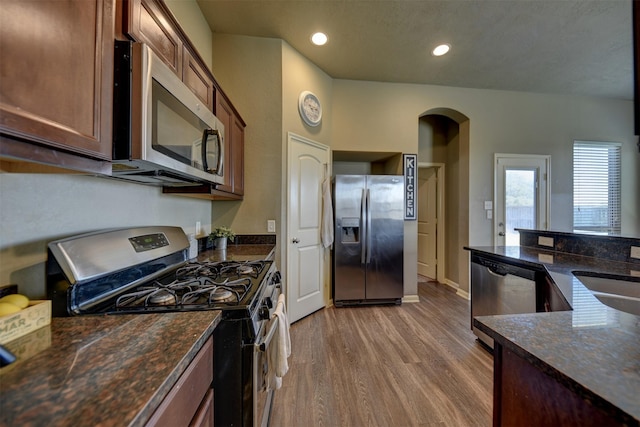 kitchen with dark stone countertops, sink, hardwood / wood-style floors, and appliances with stainless steel finishes