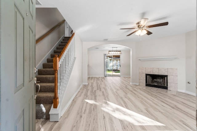 unfurnished living room with ceiling fan, light hardwood / wood-style floors, and a tile fireplace