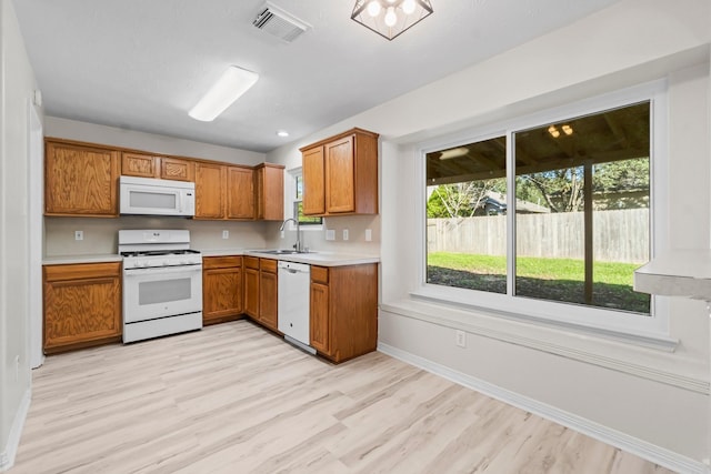 kitchen with white appliances, light hardwood / wood-style floors, and sink