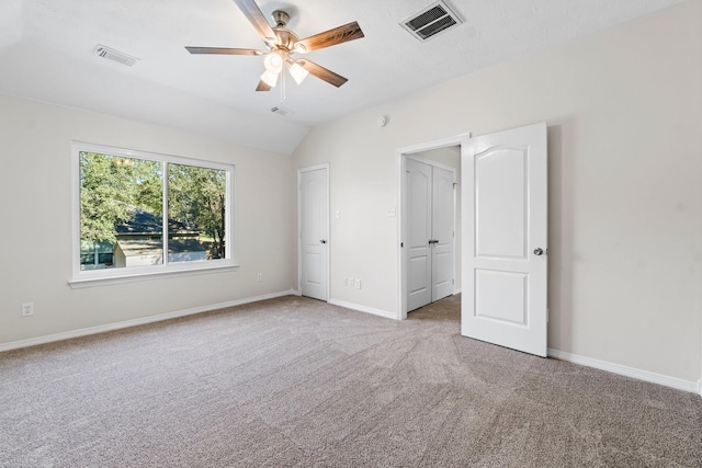 unfurnished bedroom featuring carpet flooring, vaulted ceiling, and ceiling fan