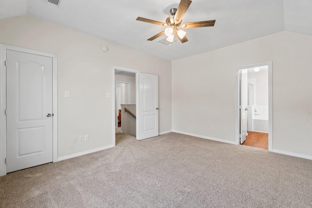 unfurnished bedroom with ceiling fan, light colored carpet, lofted ceiling, and connected bathroom