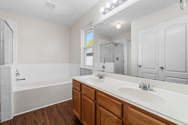 bathroom with hardwood / wood-style flooring, vanity, and plus walk in shower