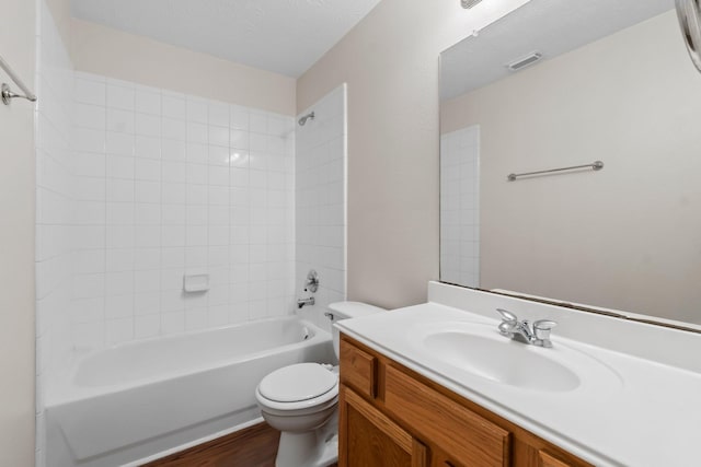 full bathroom with hardwood / wood-style floors, a textured ceiling, toilet, vanity, and tiled shower / bath