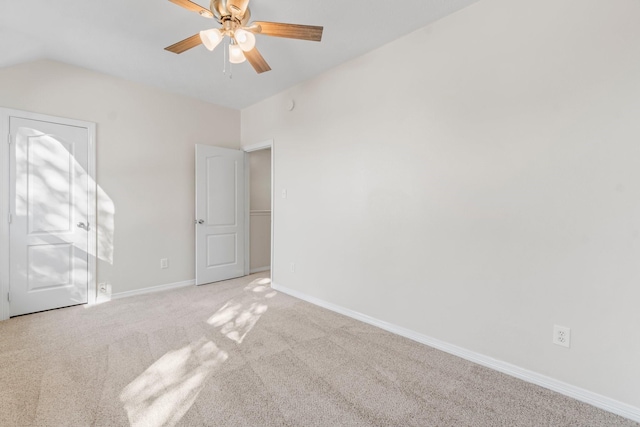 carpeted spare room with ceiling fan and vaulted ceiling