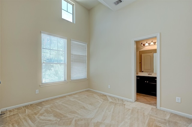 unfurnished bedroom with light carpet, ensuite bathroom, and multiple windows