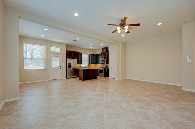 kitchen with ceiling fan, a center island, decorative backsplash, light tile patterned floors, and appliances with stainless steel finishes