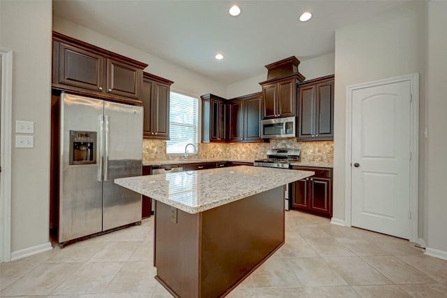 kitchen with sink, light tile patterned floors, a kitchen island, light stone counters, and stainless steel appliances