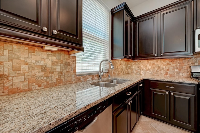 kitchen with light stone countertops, dark brown cabinets, tasteful backsplash, and sink