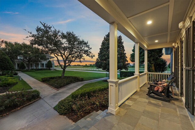 patio terrace at dusk with a lawn and covered porch