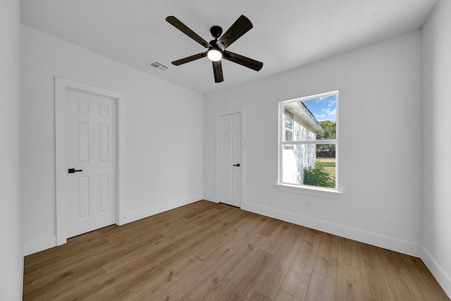 empty room with ceiling fan and light hardwood / wood-style flooring