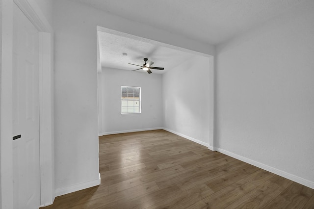 empty room with ceiling fan, wood-type flooring, and a textured ceiling