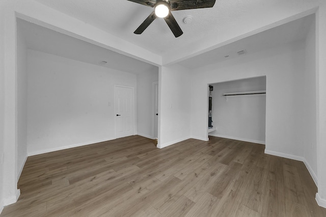 unfurnished bedroom with a textured ceiling, a closet, light hardwood / wood-style floors, and ceiling fan