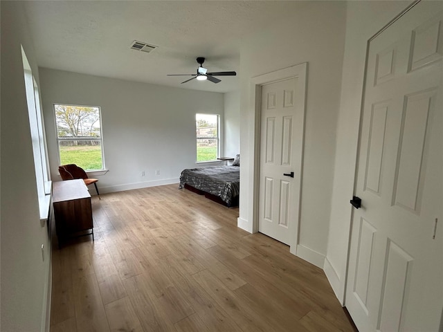 bedroom featuring ceiling fan, a textured ceiling, and light wood-type flooring