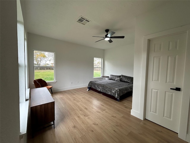 bedroom with ceiling fan, light hardwood / wood-style flooring, and multiple windows