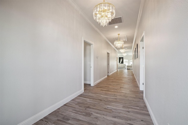 corridor with wood-type flooring, an inviting chandelier, and crown molding