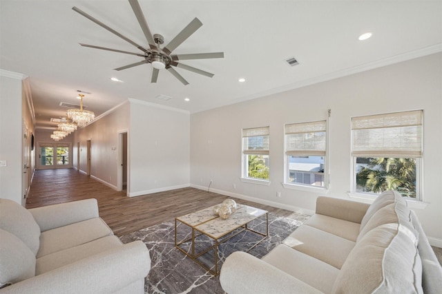 living room with ceiling fan with notable chandelier, dark hardwood / wood-style flooring, crown molding, and a healthy amount of sunlight