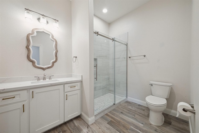 bathroom with hardwood / wood-style floors, vanity, toilet, and a shower with door