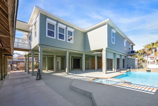 rear view of property featuring a patio area and a pool with hot tub