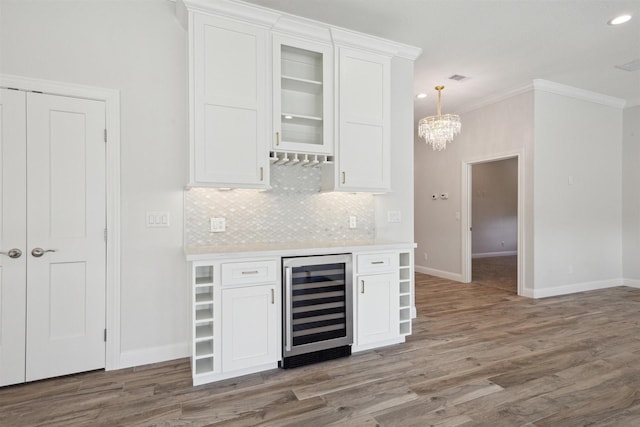 kitchen with white cabinets, hardwood / wood-style floors, wine cooler, and crown molding