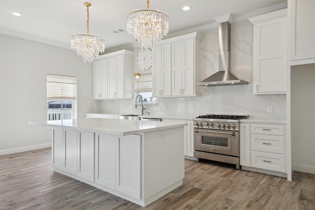 kitchen with high end stove, white cabinetry, a kitchen island, and wall chimney exhaust hood