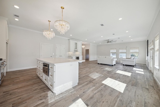 kitchen with white cabinets, light wood-type flooring, a center island, and hanging light fixtures