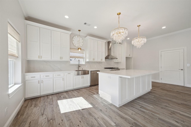 kitchen featuring decorative light fixtures, a healthy amount of sunlight, and wall chimney range hood