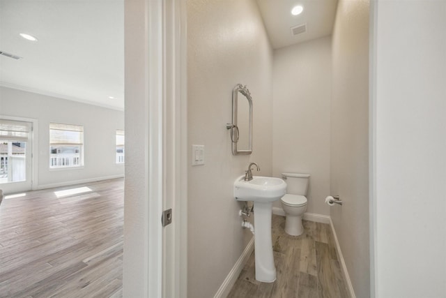 bathroom featuring ornamental molding, wood-type flooring, and toilet