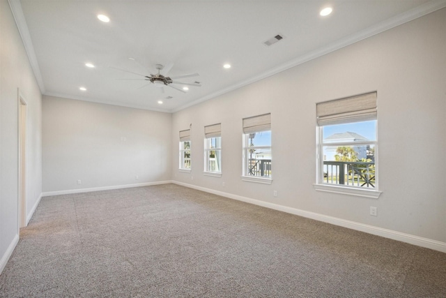 carpeted spare room with ceiling fan, plenty of natural light, and ornamental molding