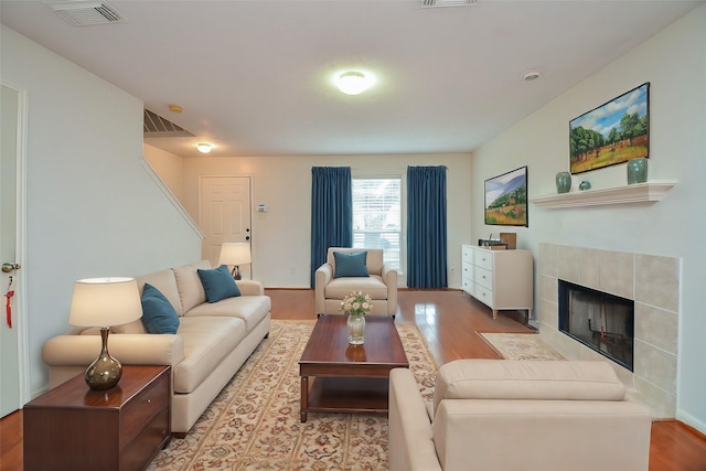 living room with a tile fireplace and light hardwood / wood-style flooring