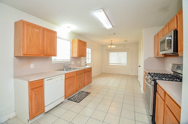 kitchen with a healthy amount of sunlight, sink, appliances with stainless steel finishes, and an inviting chandelier