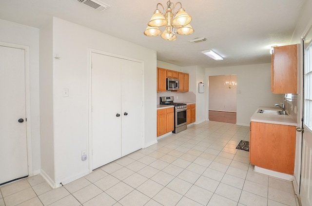 kitchen with sink, an inviting chandelier, decorative light fixtures, light tile patterned flooring, and appliances with stainless steel finishes