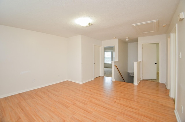 empty room featuring a textured ceiling and light hardwood / wood-style flooring