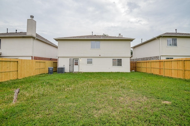 back of property with central AC and a lawn