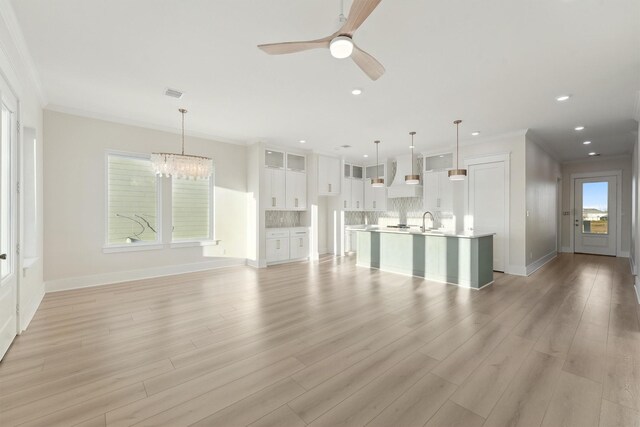 unfurnished living room featuring light hardwood / wood-style floors, plenty of natural light, and ornamental molding