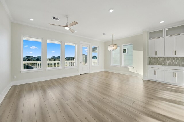 unfurnished living room featuring ceiling fan with notable chandelier, light hardwood / wood-style flooring, and ornamental molding