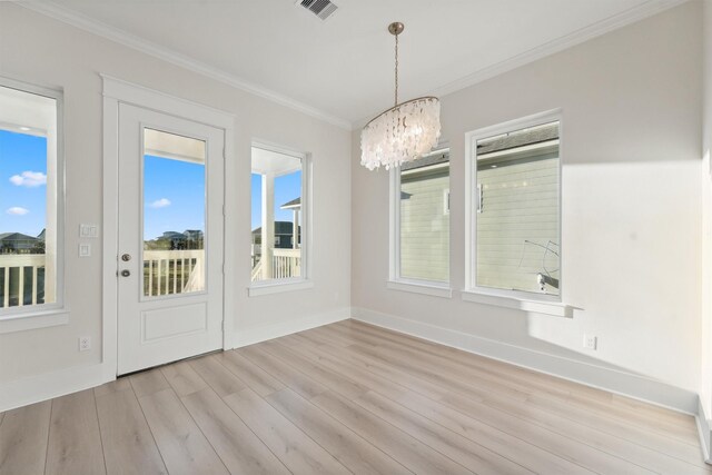 unfurnished dining area with light hardwood / wood-style floors, crown molding, and a chandelier