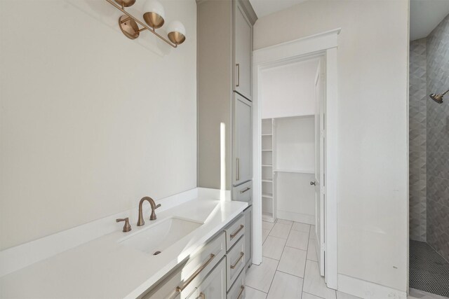 bathroom featuring tile patterned flooring, vanity, and tiled shower