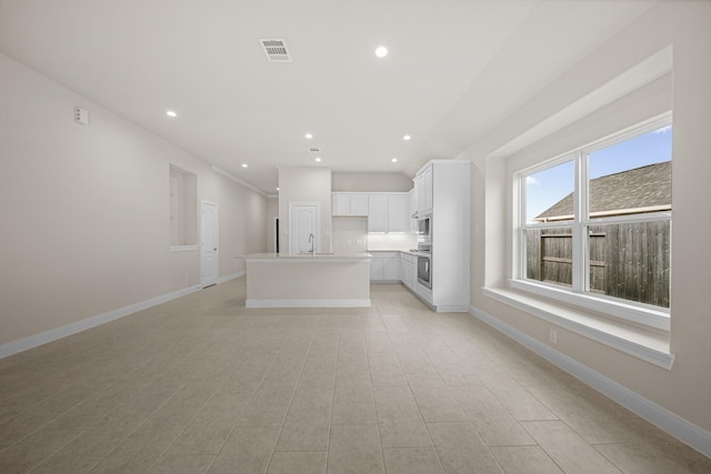 unfurnished living room with visible vents, baseboards, a sink, and recessed lighting