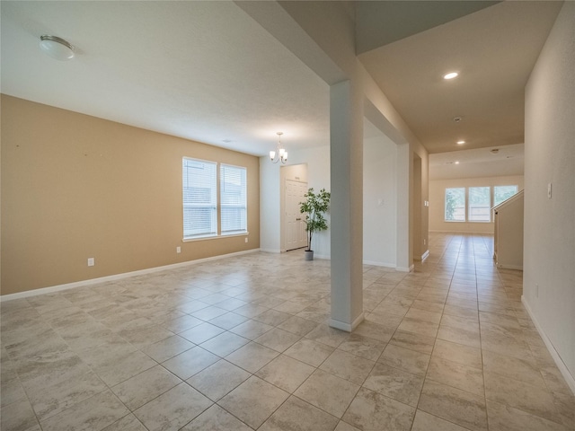 tiled empty room featuring an inviting chandelier