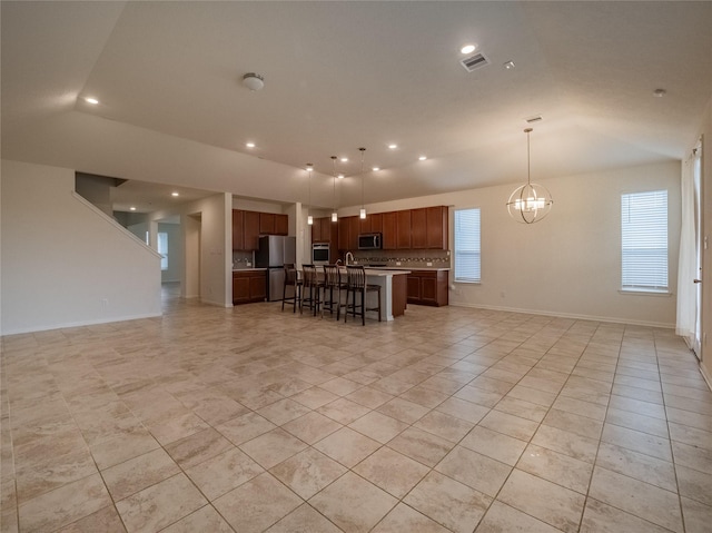 kitchen with a breakfast bar, a center island, appliances with stainless steel finishes, decorative light fixtures, and a chandelier