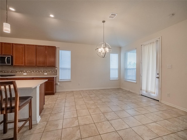 kitchen with decorative backsplash, a breakfast bar, light tile patterned floors, a notable chandelier, and hanging light fixtures