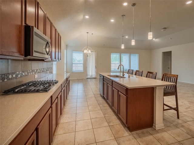 kitchen with appliances with stainless steel finishes, sink, hanging light fixtures, a breakfast bar area, and an island with sink