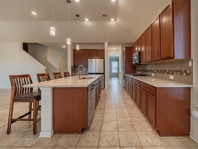 kitchen featuring pendant lighting, sink, a breakfast bar area, an island with sink, and stainless steel appliances