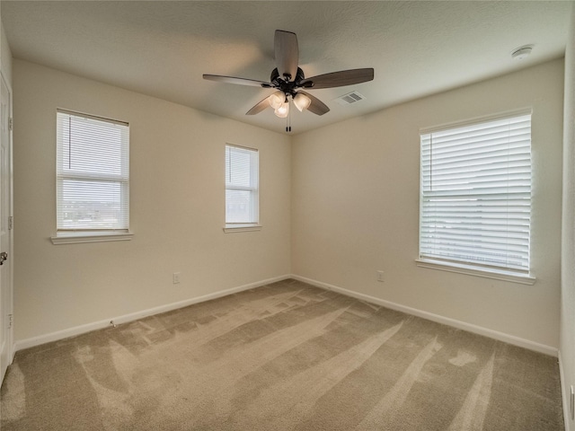 empty room featuring carpet flooring, ceiling fan, and a healthy amount of sunlight