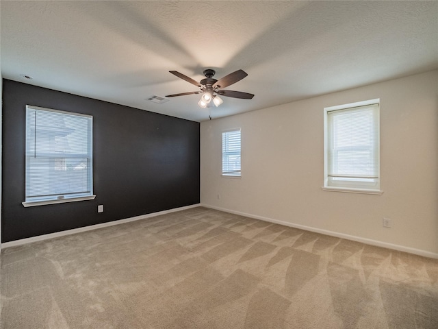 carpeted spare room featuring a textured ceiling and ceiling fan